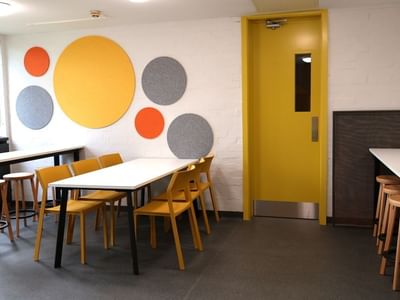 Colorful meeting room with round acoustic panels and yellow chairs at La Trobe University – Menzies College.