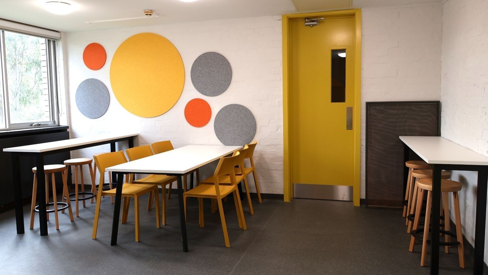 Colorful meeting room with round acoustic panels and yellow chairs at La Trobe University – Menzies College.