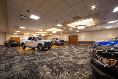 Trucks and cars parked on patterned carpet by a wood floor, under pendant lights at Glenmore Inn & Convention Centre