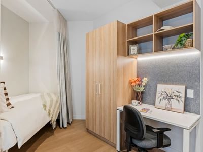 Modern room at UniLodge Brisbane City with bed, desk, and wooden closet.