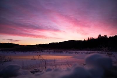 Winter sunrise with pink skies over a frozen lake at Adirondack Mountains in The Lodge at Schroon Lake