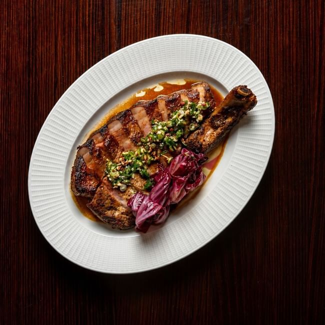 Grilled steak with herb topping and pickled onions on a white plate for NRL Grand Final Dining