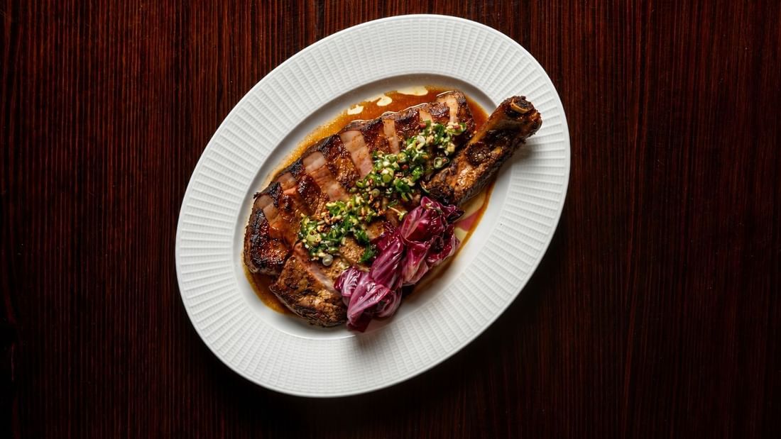 Grilled steak with herb topping and pickled onions on a white plate for NRL Grand Final Dining