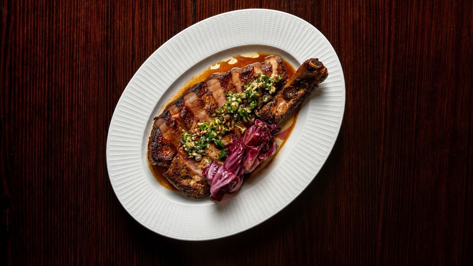 Grilled steak with herb topping and pickled onions on a white plate for NRL Grand Final Dining