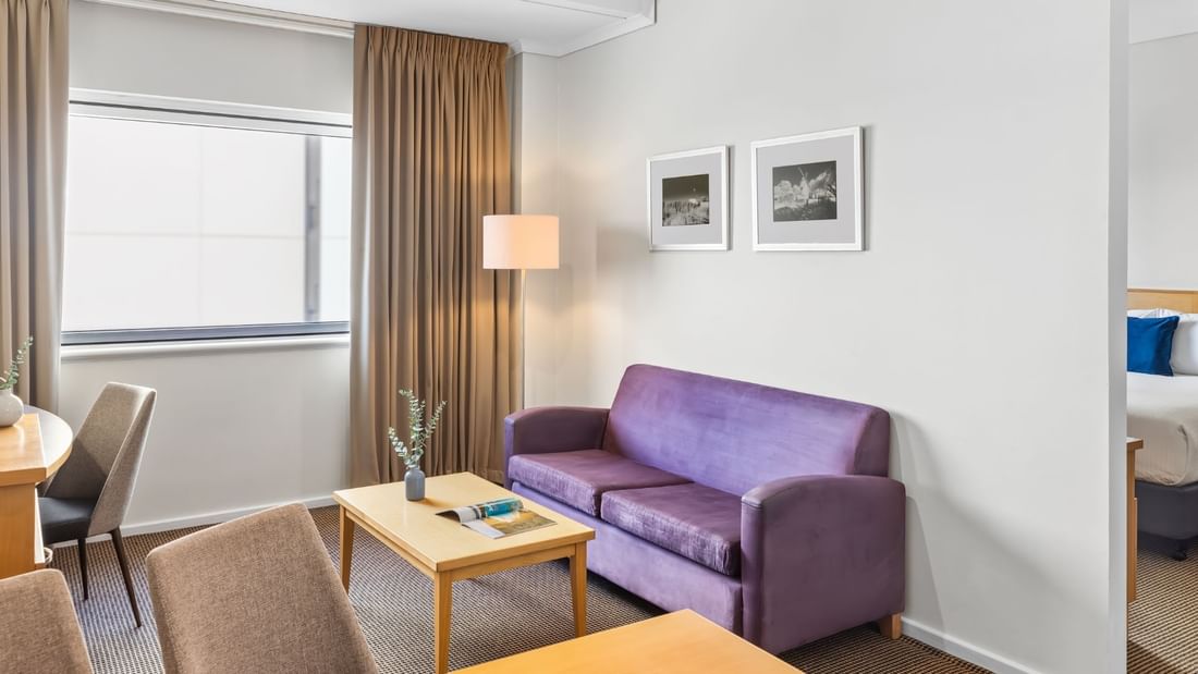 Living room area in an Apartment at Novotel Perth Langley with dining table, sofa, TV and a work desk
