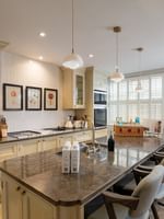 Kitchen with a marble island by bar chairs and pendant lights in Penthouse at The Capital Hotel, Apartments & Townhouse