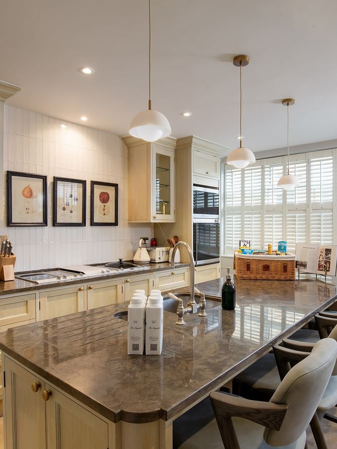 Kitchen with marble island, bar seating, and pendant lights in penthouse at The Capital Hotel & Townhouse
