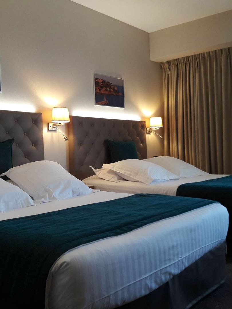 Deux lits queen size avec lampes de chevet dans la chambre familiale du Splendid Hotel & Spa Nice