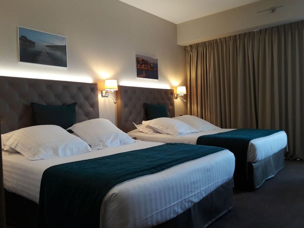 Deux lits queen size avec lampes de chevet dans la chambre familiale du Splendid Hotel & Spa Nice
