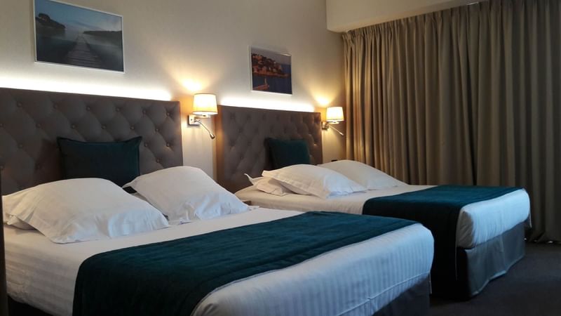 Two queen beds with bedside lamps in the Family Room at Splendid Hotel & Spa Nice