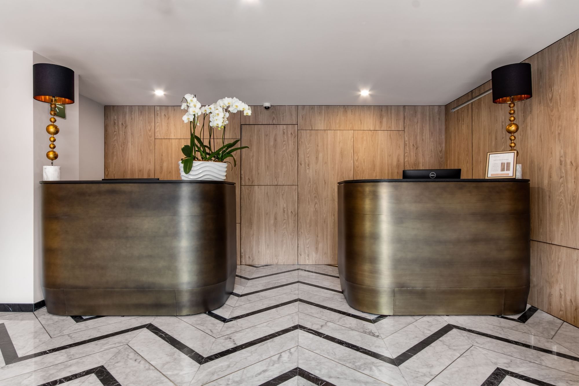 Modern hotel lobby with sleek counters, white orchids, and geometric flooring at Elements by Marquis