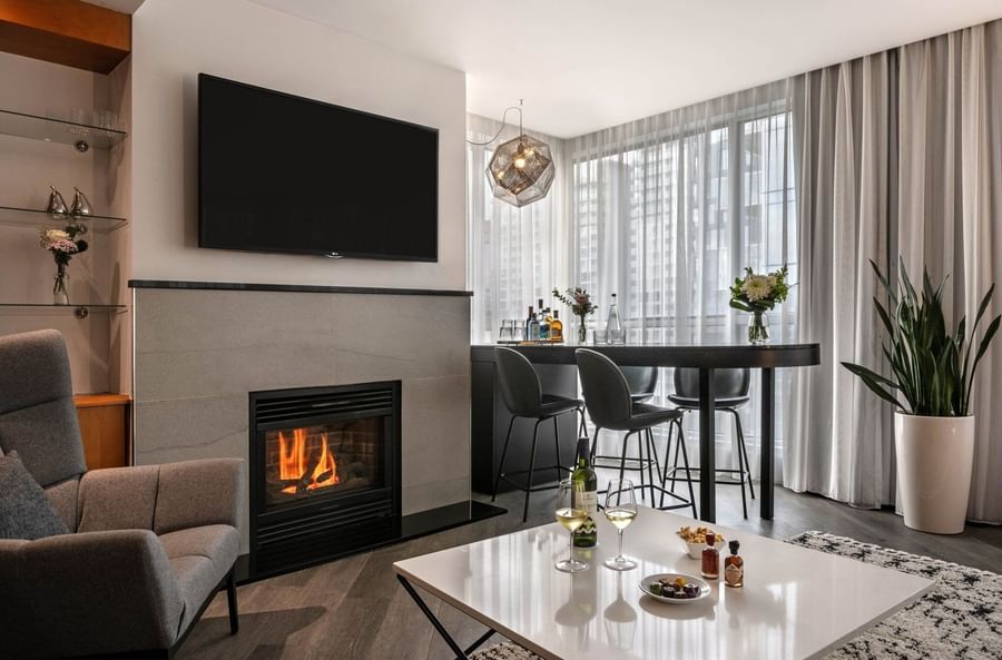TV lounge with fireplace and dining area near the window in Penthouse Sainte-Catherine at Warwick Le Crystal Montreal