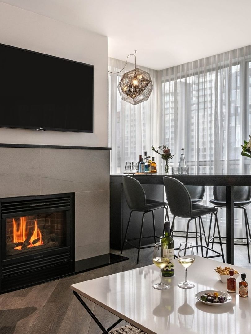Élégant salon avec cheminée, table à manger et vue sur la ville au Warwick Le Crystal – Montréal, à Montréal.
