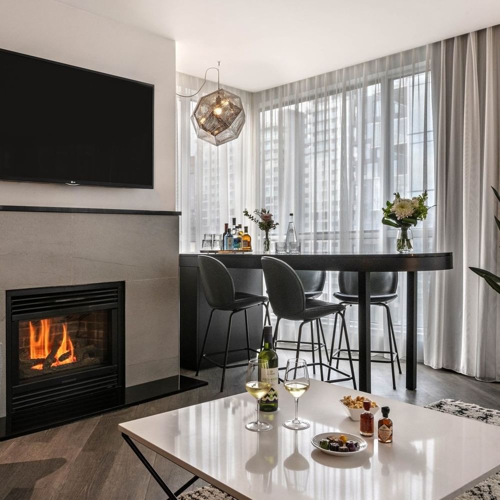 TV lounge with a fireplace, a coffee table with wine, by a bar in Penthouse Sainte-Catherine at Warwick Le Crystal Montreal