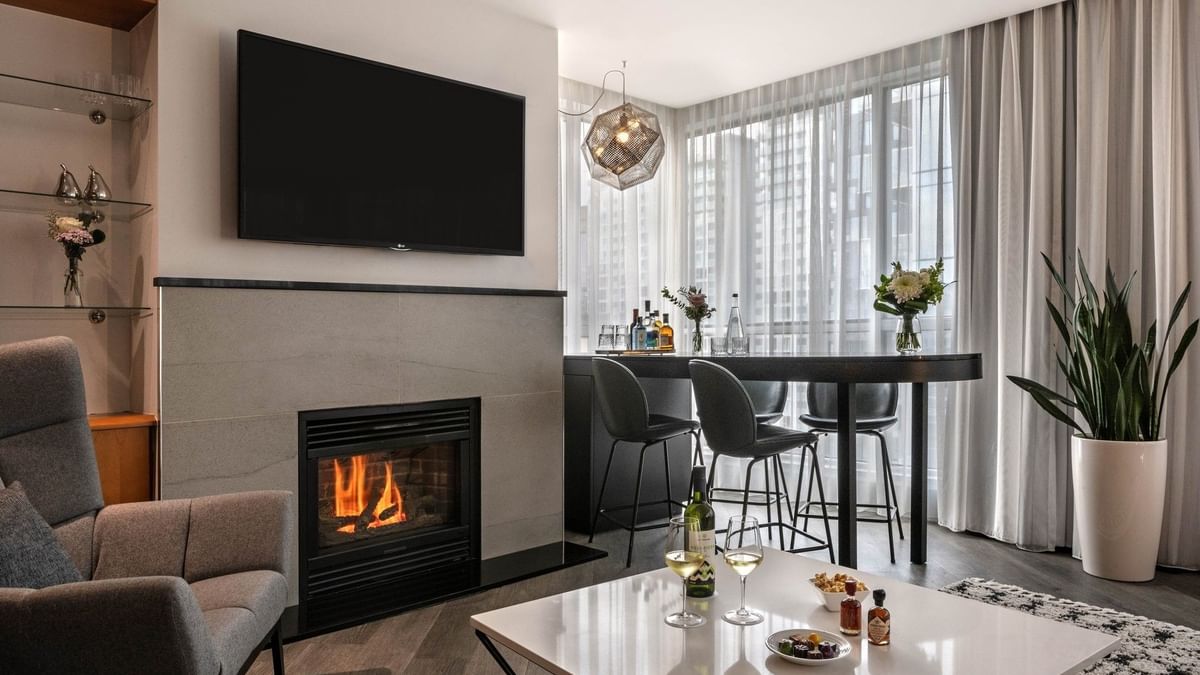 Élégant salon avec cheminée, table à manger et vue sur la ville au Warwick Le Crystal – Montréal, à Montréal.