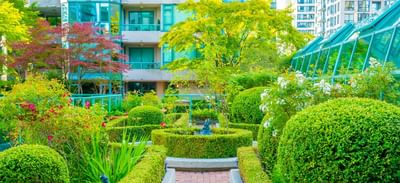 Lush green courtyard garden with a fountain and manicured hedges at Rosedale on Robson Suite Hotel
