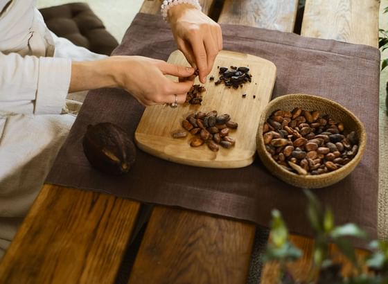 Hands sort cocoa beans on a wooden board during a chocolate-making workshop at Ibagari Hotel