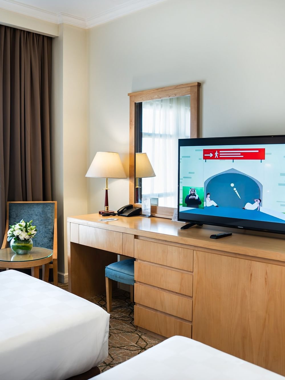 ثلاثة أسرّة ومكتب مع تلفزيون وكرسي في الغرفة الخماسية القياسية في فندق سجى ورويك المدينة المنورة.