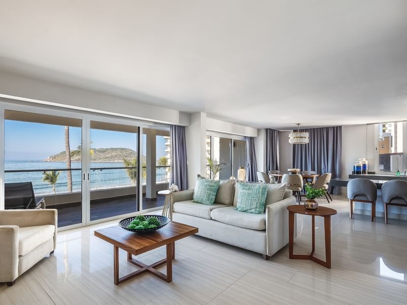 Penthouse living room with a grey sofa, a wooden coffee table, and an ocean-view balcony at Sunvivia Mazatlán
