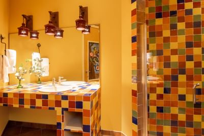 Bathroom vanity with fresh flowers, towels & colorful tiles in King Premiere Sante Fe at Retro Suites Hotel