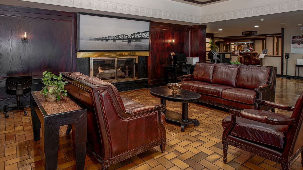 Hotel lobby with leather chairs, a fireplace, and a large framed photograph on the wall.