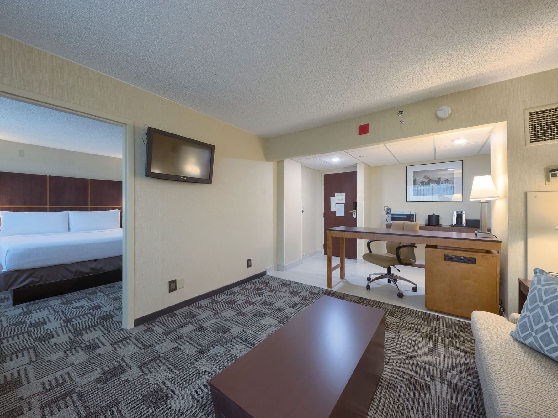 NCED Premium King Suite at NCED Hotel and Conference Center with a bed, desk, chair, couch, and TV.
