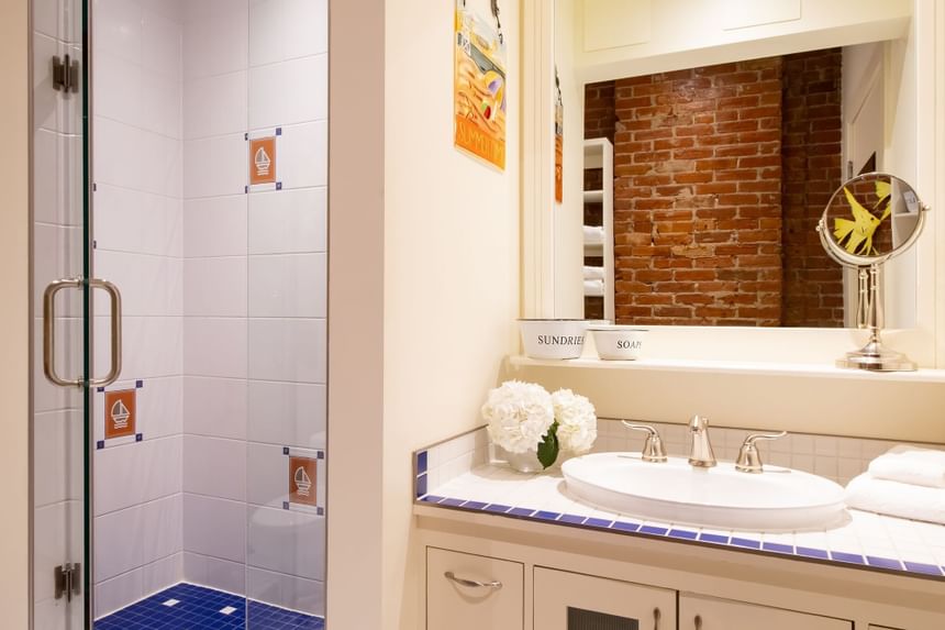 Shower area & bathroom vanity with fresh flowers & mirror of Premiere Loft Nantucket at Retro Suites Hotel