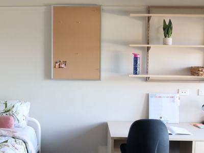 A tidy room with a bed and desk at La Trobe University - Terraces.
