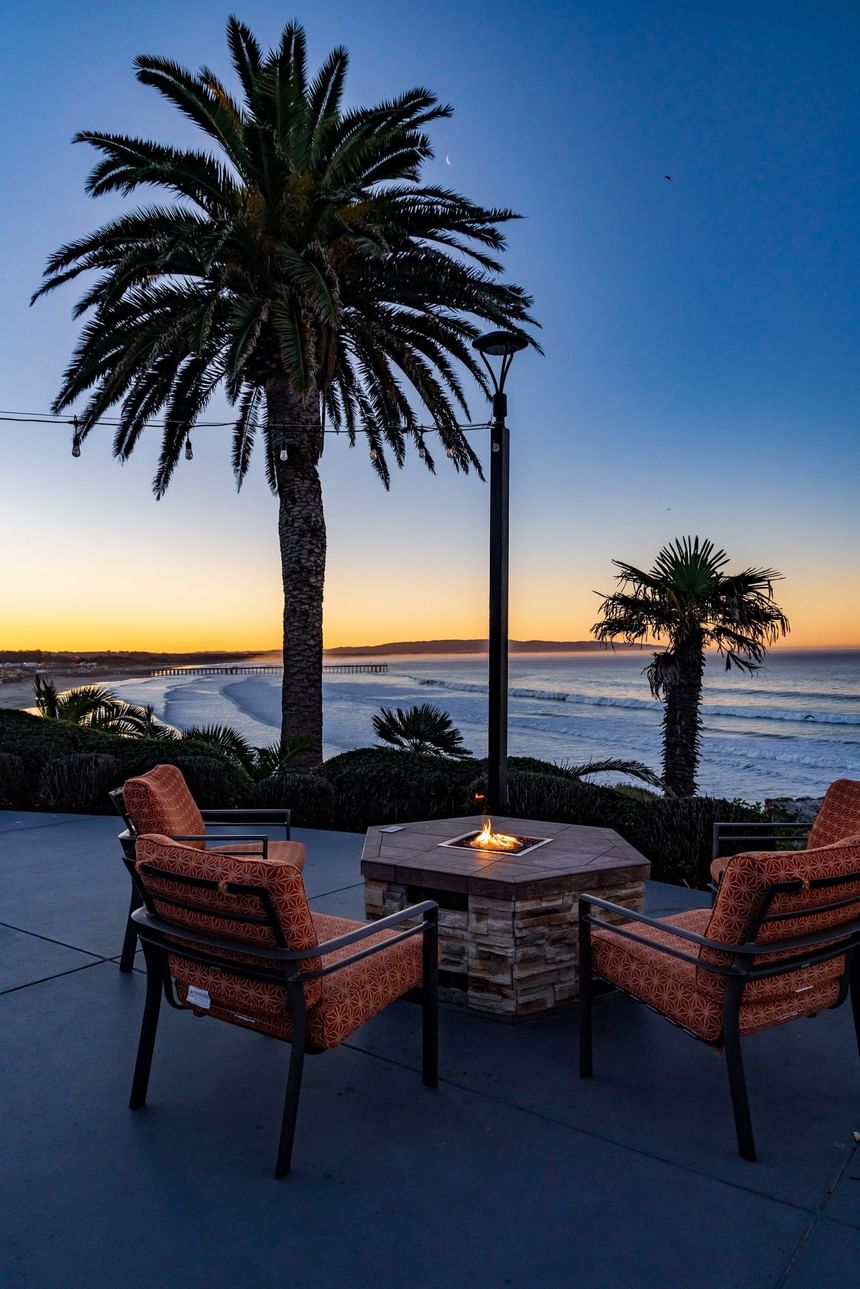 Hotel terrace fire pit with seating at sunset on the ocean 