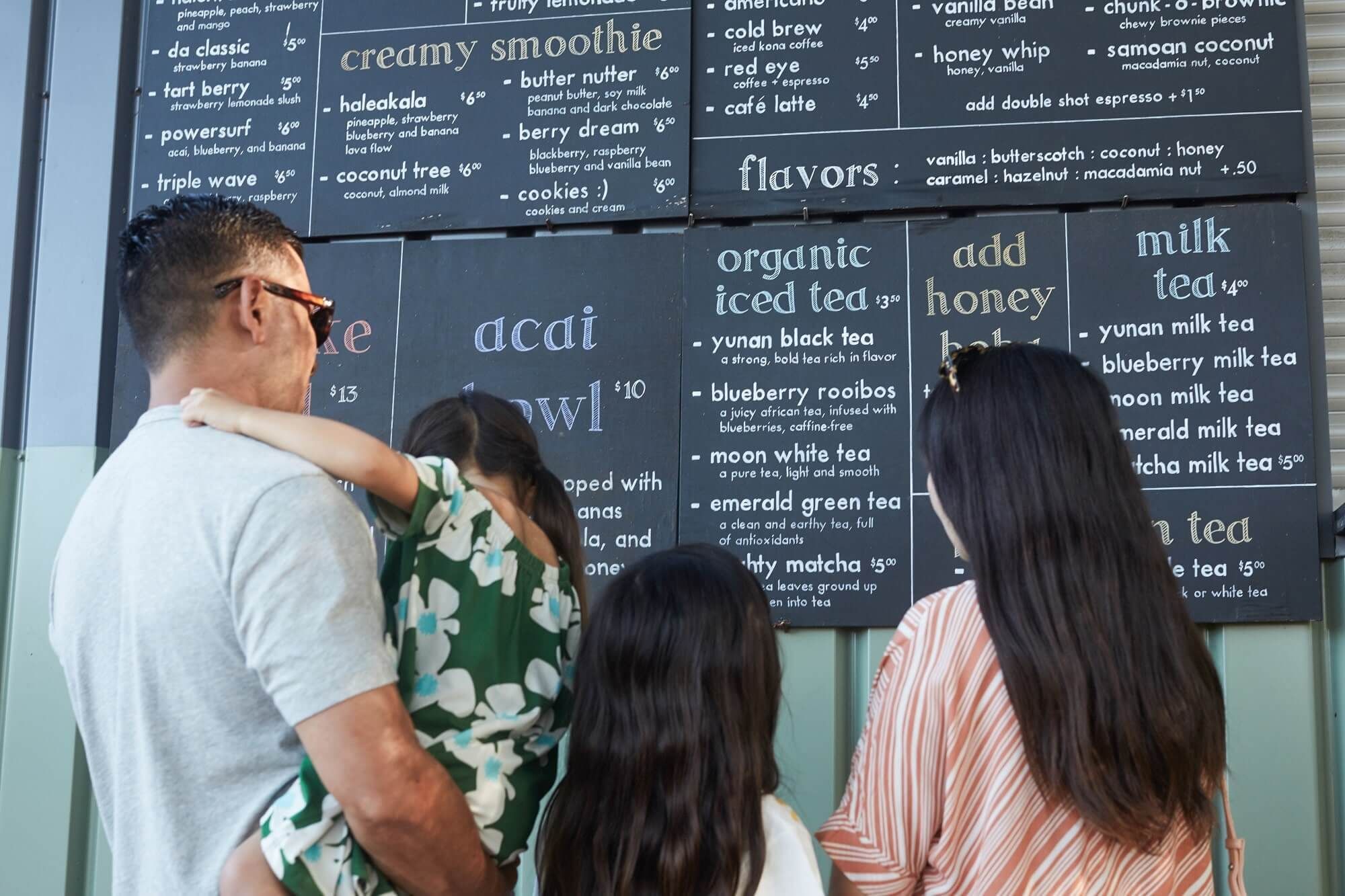 A family reading a large dining menu in Haleiwa Town near Waikiki Resort Hotel