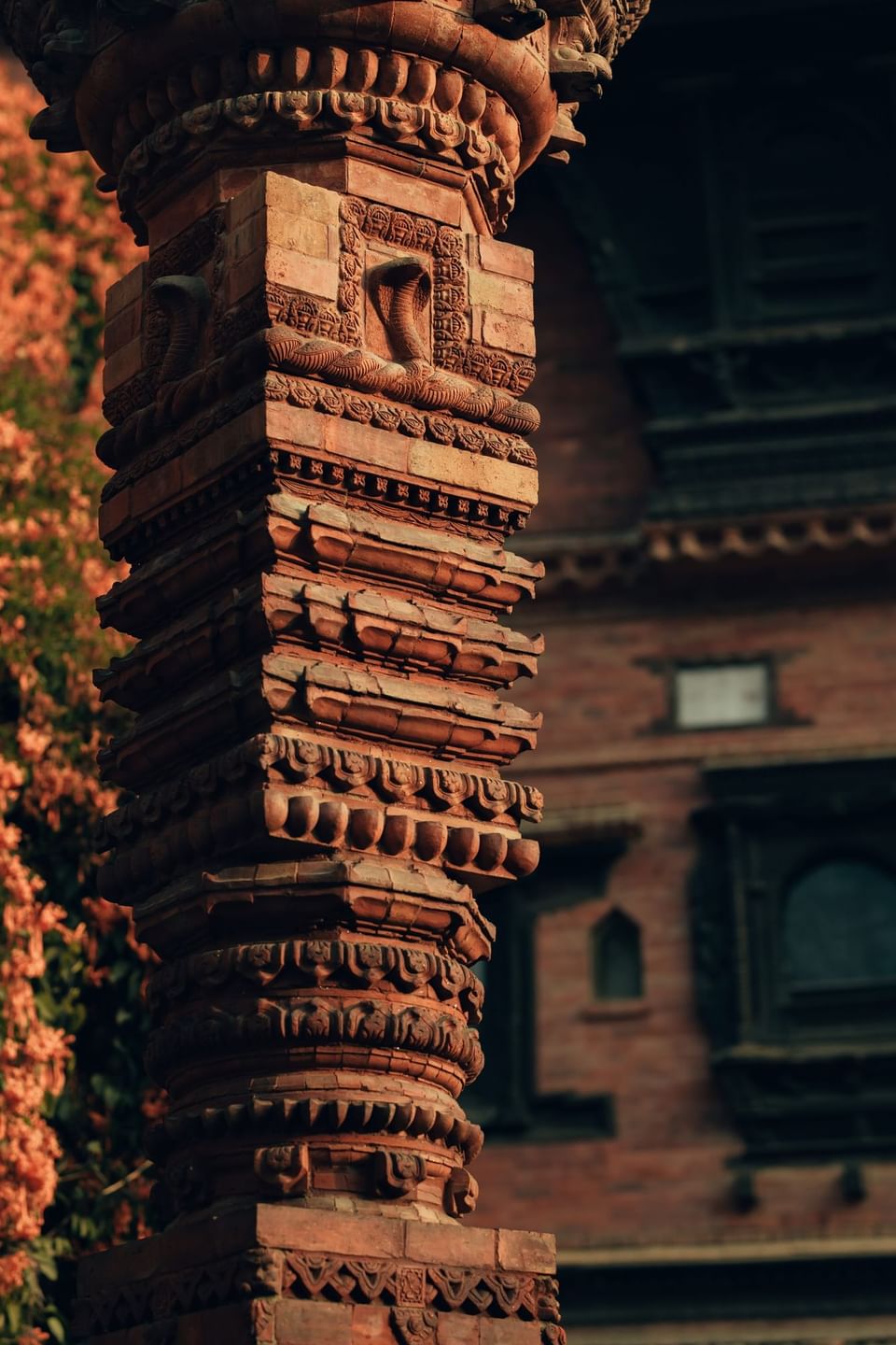 Close-up of a decorative red brick pillar with patterns in front of an old building at Dwarika's Hotel Kathmandu