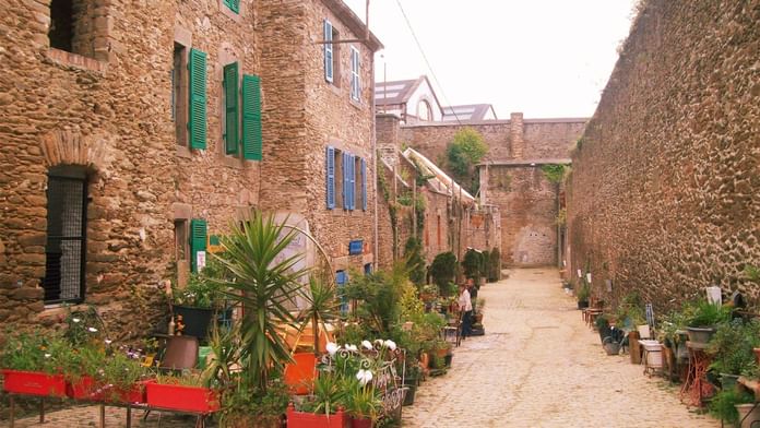 Charmante ruelle étroite avec des plantes luxuriantes et des murs en pierre près des Hôtels Oceania