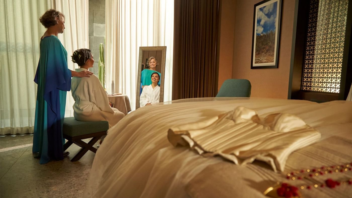 Two women looking into a mirror in a bedroom at Fiesta Americana