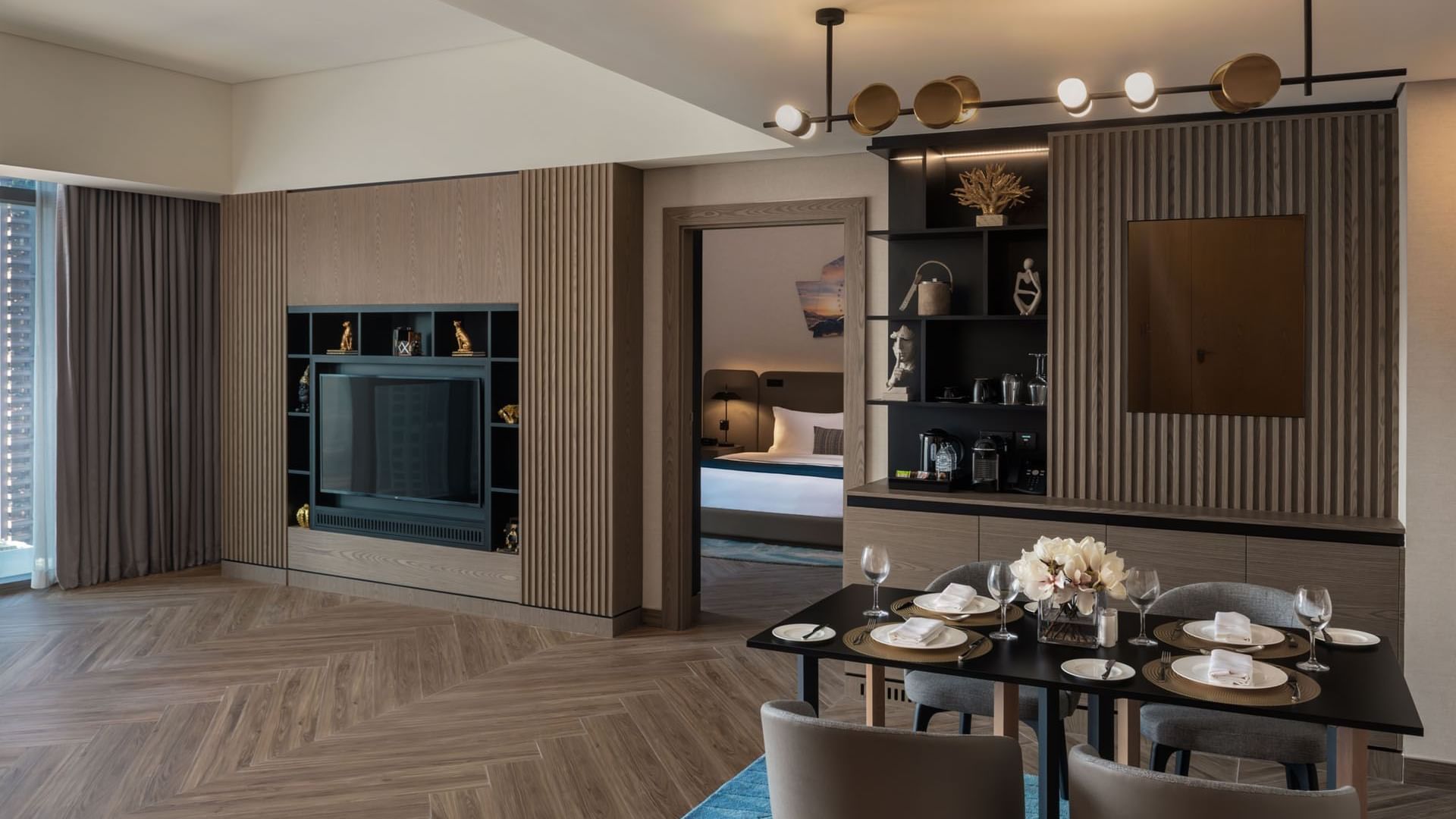 Modern hotel suite with a dining area, entertainment unit, and a view into the bedroom at Paramount Hotel Midtown