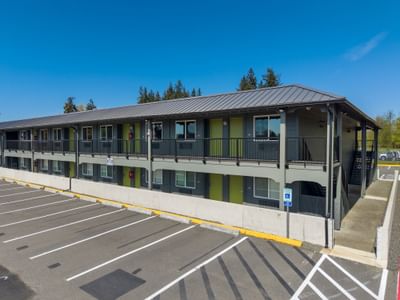 Two-story grey exterior with lime green doors and striped parking at The Varsity South