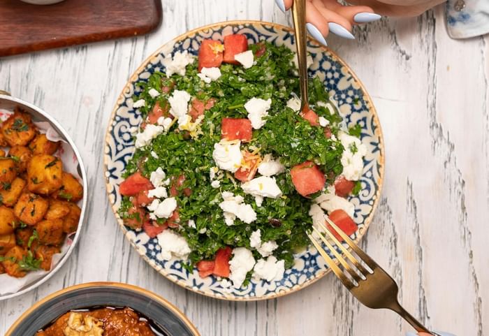 Fresh watermelon and feta salad in a patterned bowl by a gold fork at Anaheim Portofino Inn 