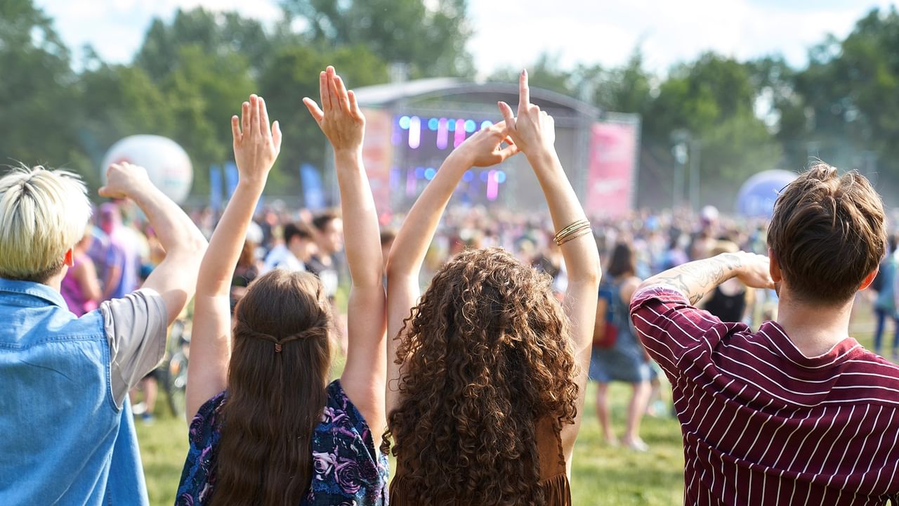 Crowd with raised hands enjoying outdoor stage performance at an outdoor summer fair