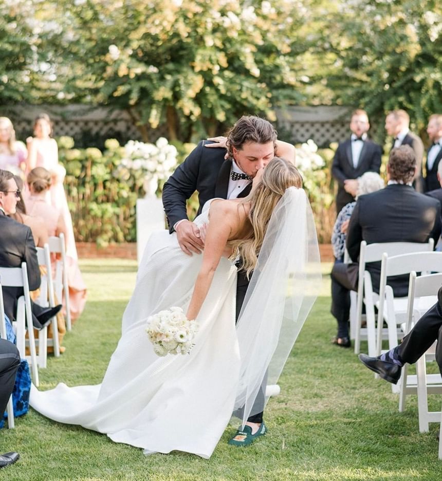 Bride and groom kiss at outdoor wedding ceremony at The Clifton Hotel in Charlottesville, Virginia.
