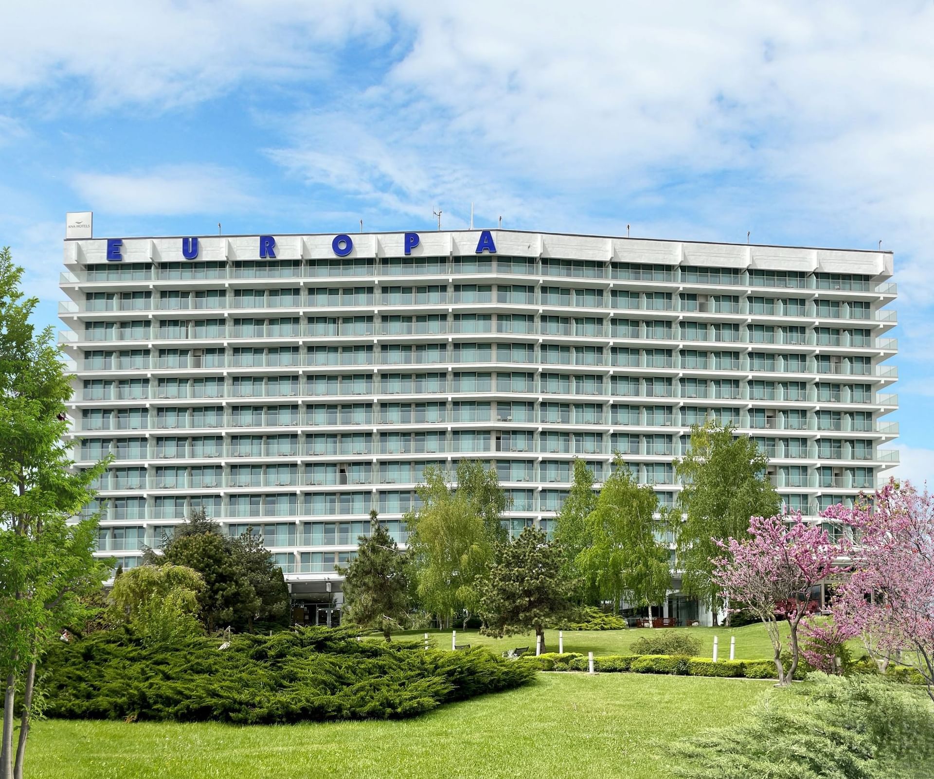 Exterior view of the Ana Hotels Europa Eforie Nord, featuring multiple glass balconies, and lush green landscaping