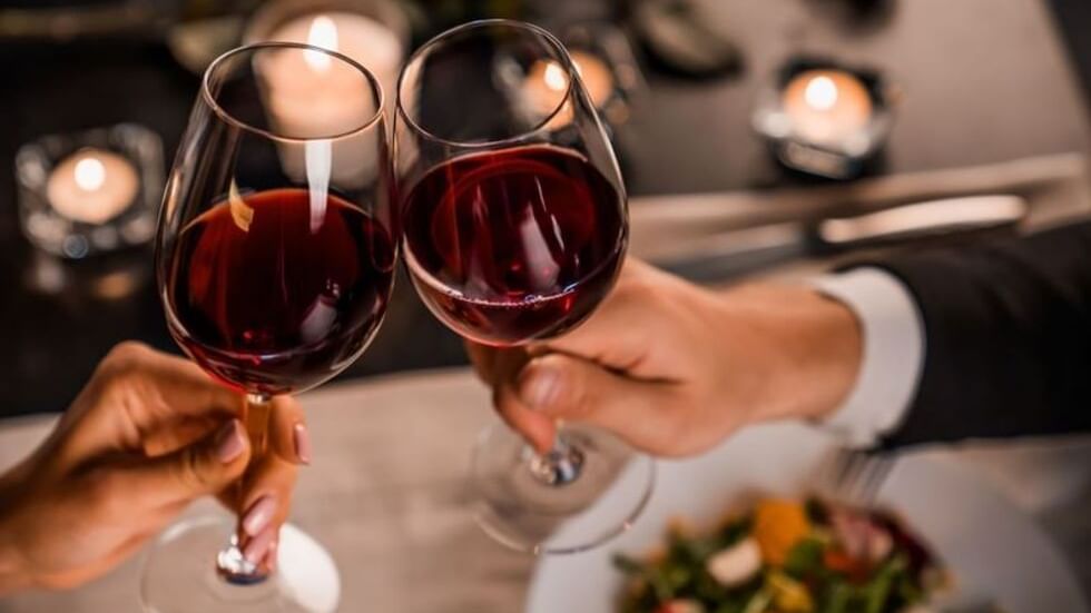 Una pareja sosteniendo copas de vino tinto en la Fiesta Americana