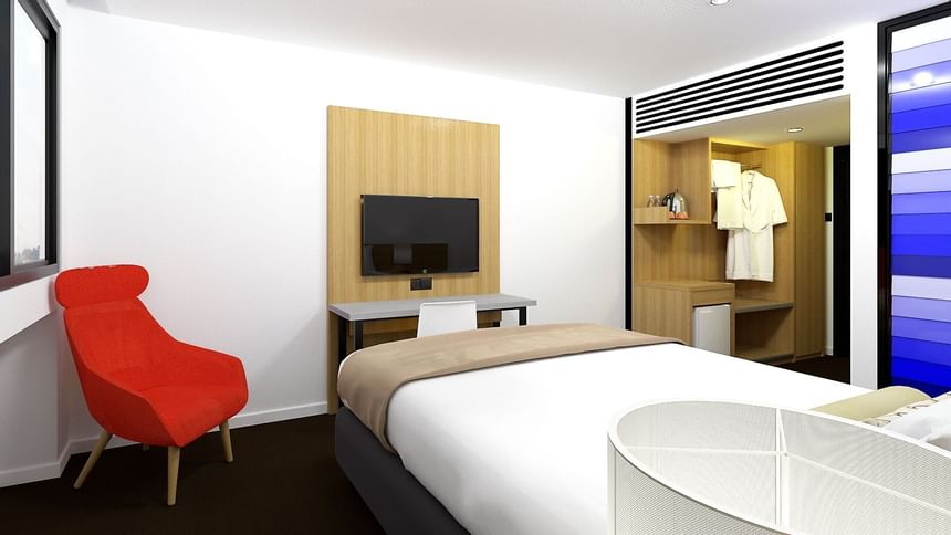 Lounge, bed, TV & closet in Deluxe Queen Room at Jasper Hotel