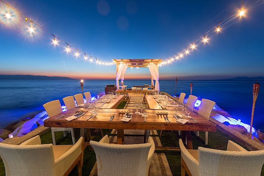 Outdoor dining set up with lights by the sea in Chet's Table at Villa Premiere Boutique Hotel & Romantic Getaway