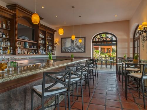 Bar La Suerte with modern stools, a marble countertop, and a view of the outdoor patio at Hacienda del Mar Los Cabos