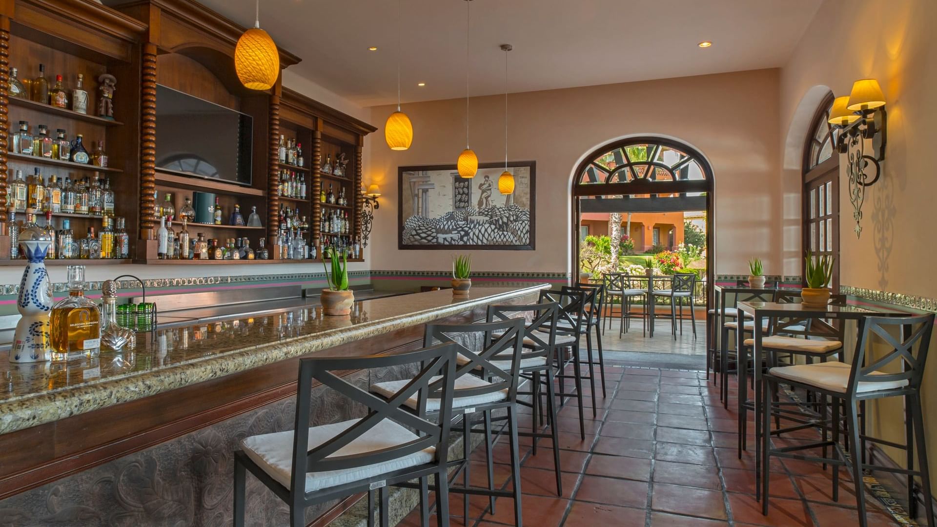 Bar La Suerte with modern stools, a marble countertop, and a view of the outdoor patio at Hacienda del Mar Los Cabos