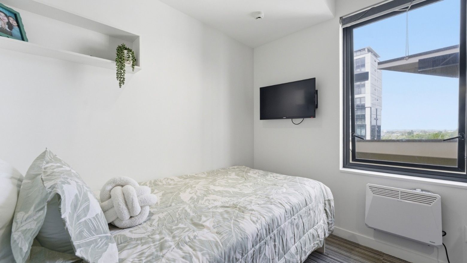 Comfortable bedroom with a bed, TV, and large window at UniLodge Auckland City.