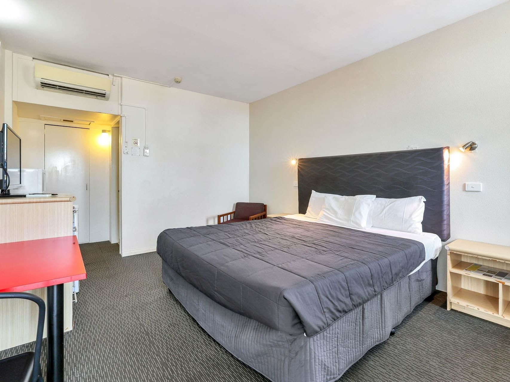 Work desk & TV facing the bed in King Room with carpeted floors at Poinciana Inn featuring Darwin CBD accommodation