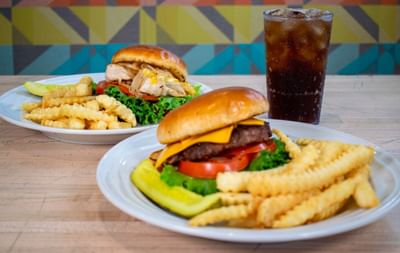 Two delicious plates featuring cheeseburgers, French fries, and a cold soda served in Oasis Grill at Centennial Plaza Resort