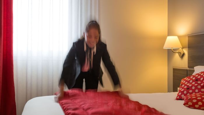 A maid preparing a bed in a room at Actuel Hotel