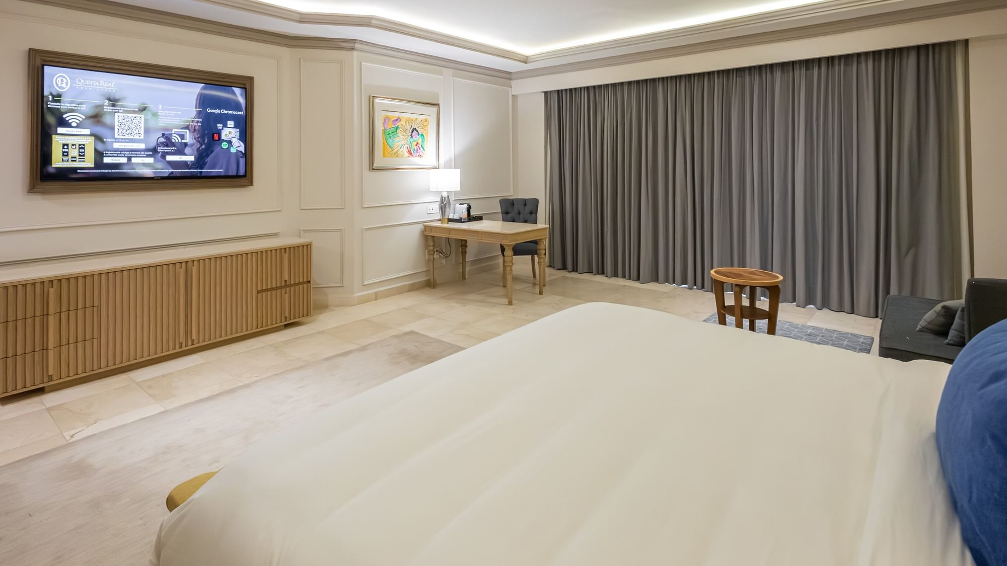 Spacious King Gran Class Gold Suite with wall-mounted TV, desk, gray curtains at Quinta Real Monterrey.