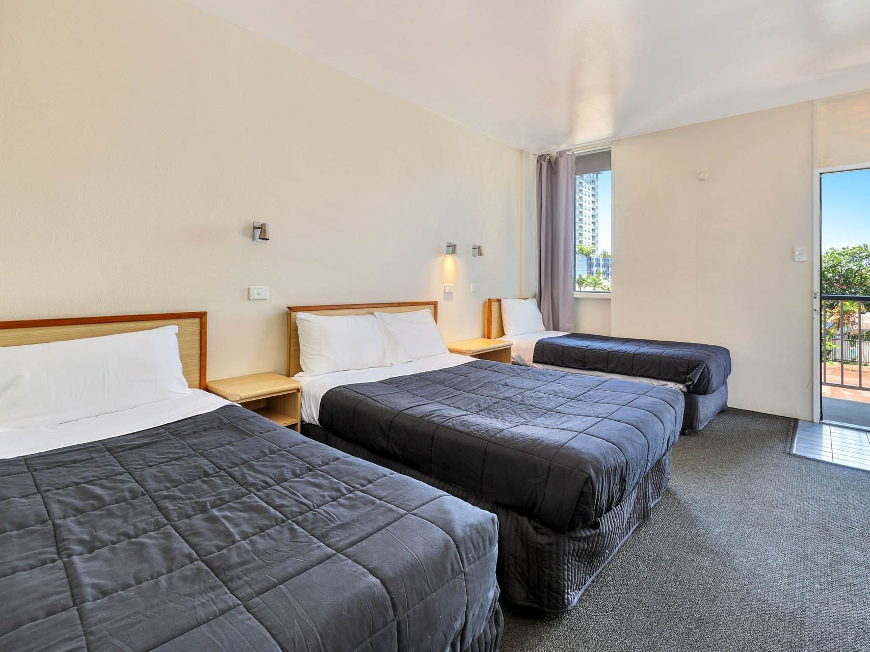 Nightstands by the beds in Standard Triple with carpeted floors at Poinciana Inn featuring Darwin accommodation near airport